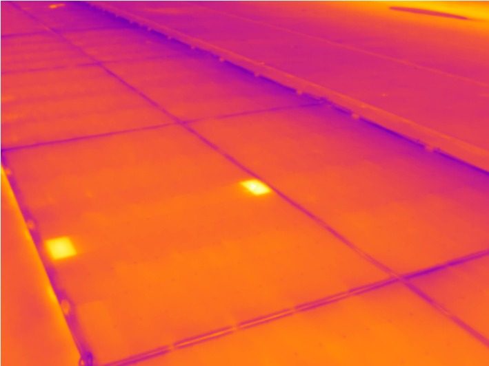 Thermografieaufnahme einer flach montierten Modulreihe mit zwei punktuell erwärmten Stellen